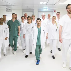 Ansatte kledd i hvitt går ned sykehuskorridor