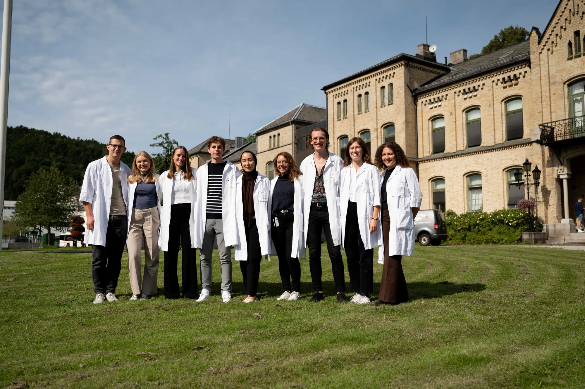 En gruppe mennesker som poserer for et bilde foran en bygning