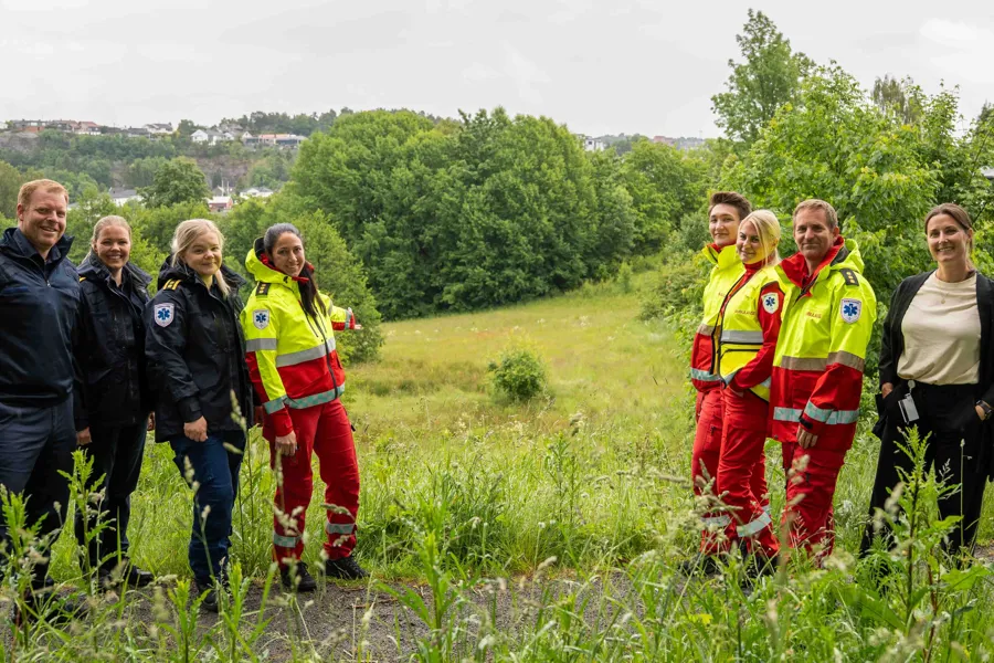 En gruppe mennesker som står på et jorde, flere i ambulanseuniform