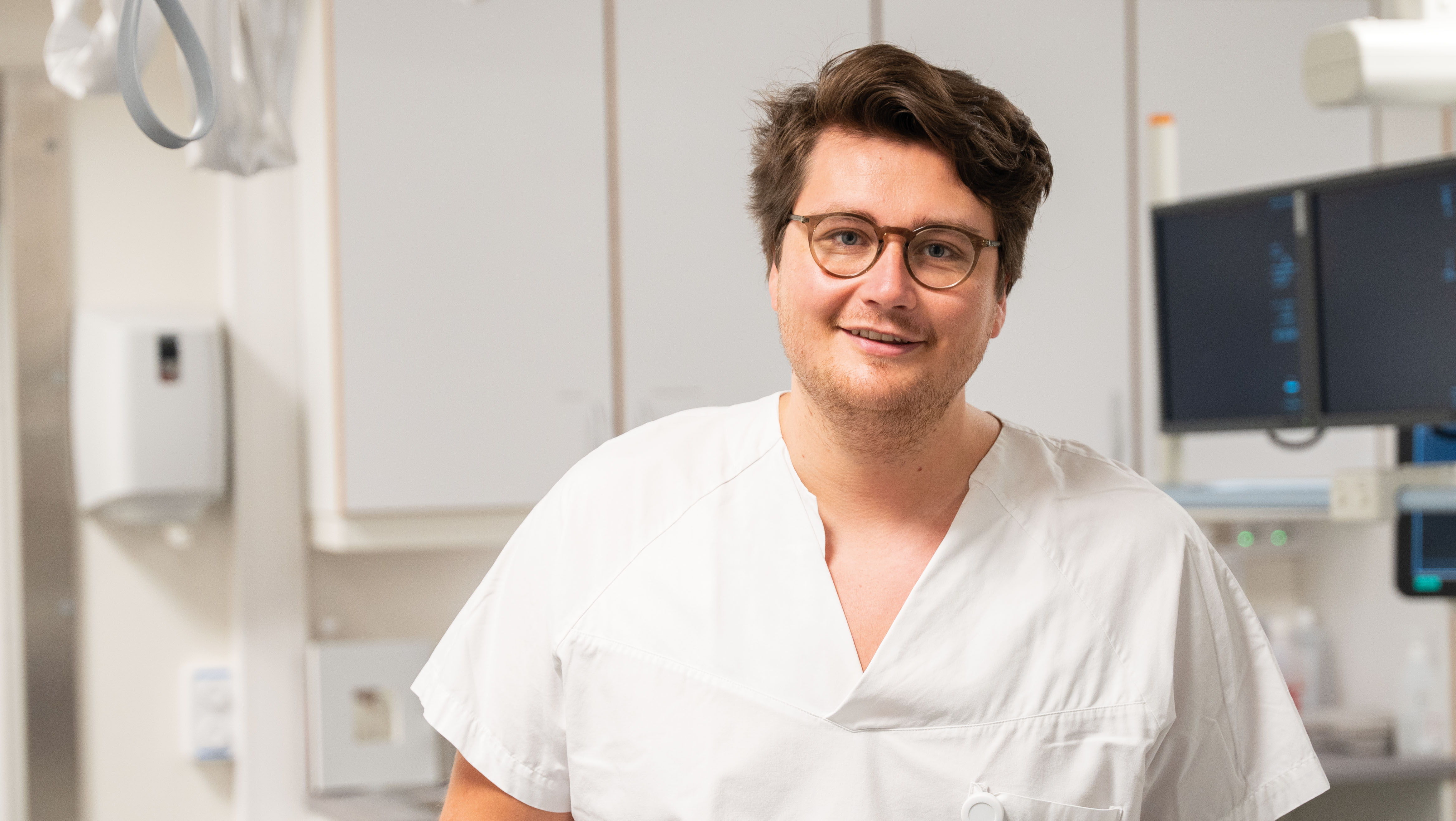 Lis-lege kledd i hvit uniform smiler mot kamera.