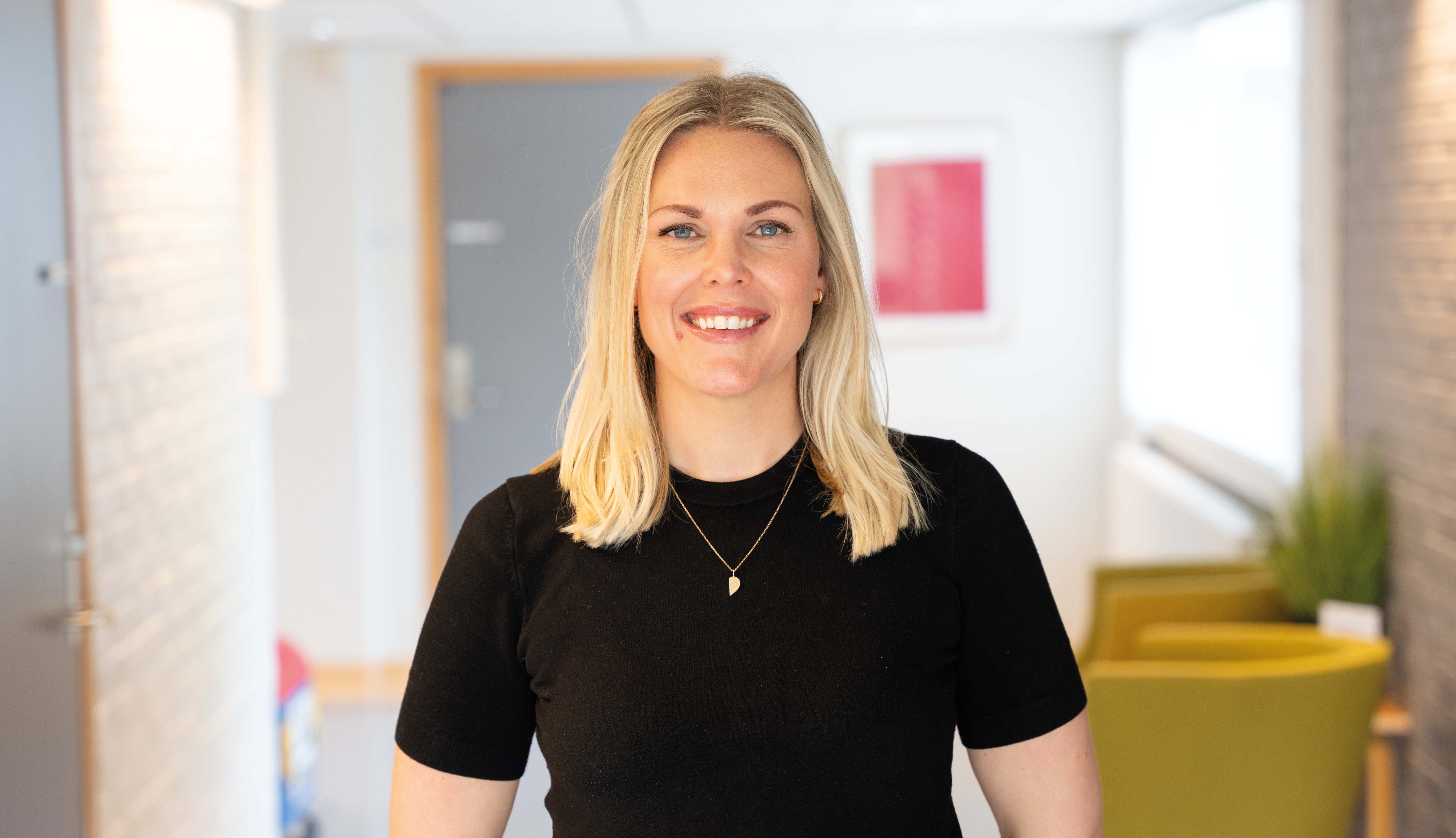 En psykologspesialist står smilende i en sykehuskorridor.