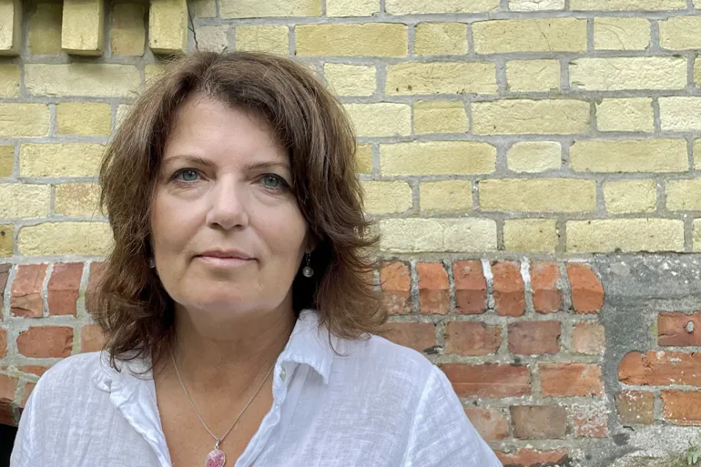 Bilde viser forsker Åshild Tellefsen Håland utenfor et gult mursteinsbygg.