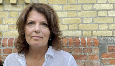 Bilde viser forsker Åshild Tellefsen Håland utenfor et gult mursteinsbygg.