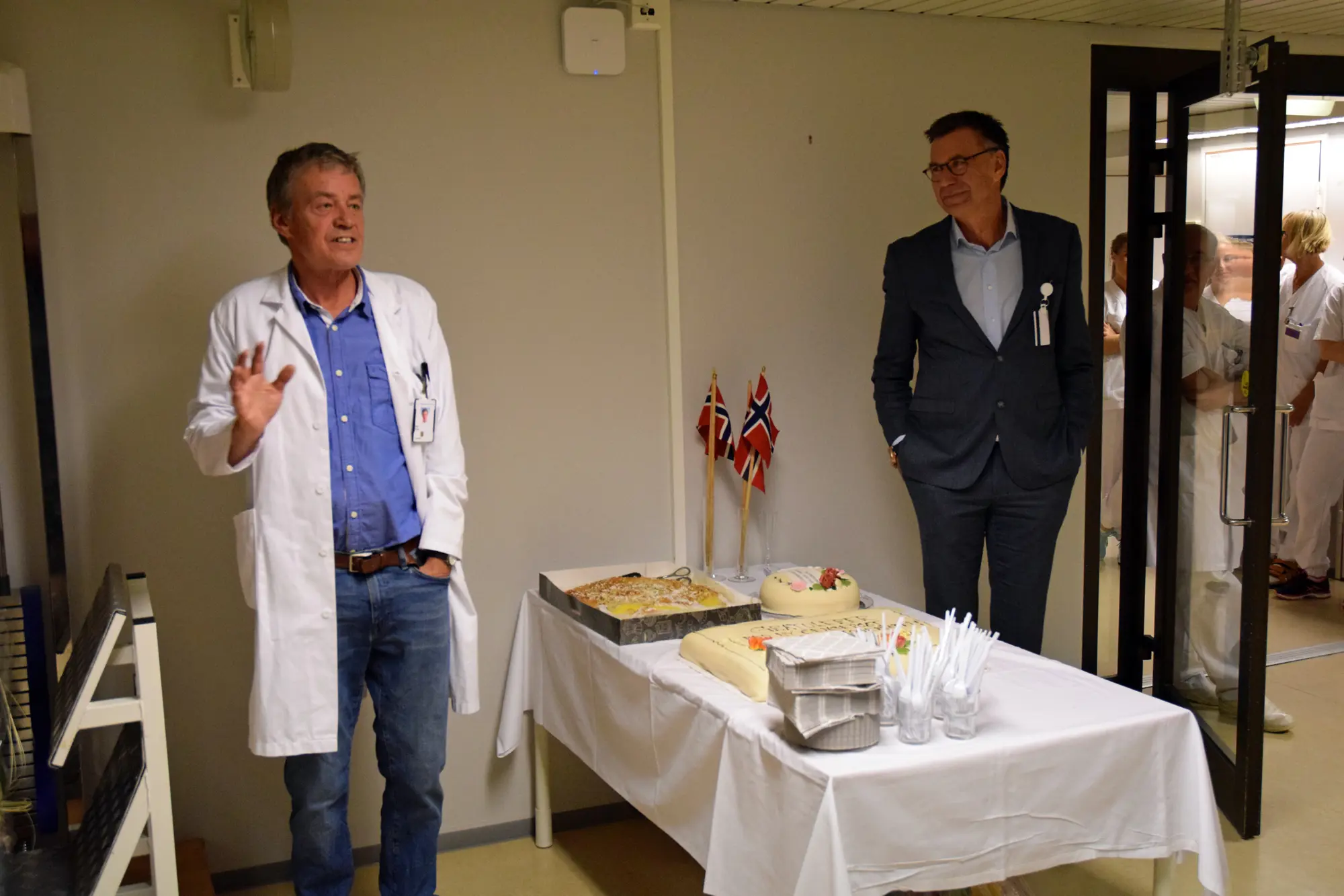 Et par menn som står ved siden av et bord med mat på