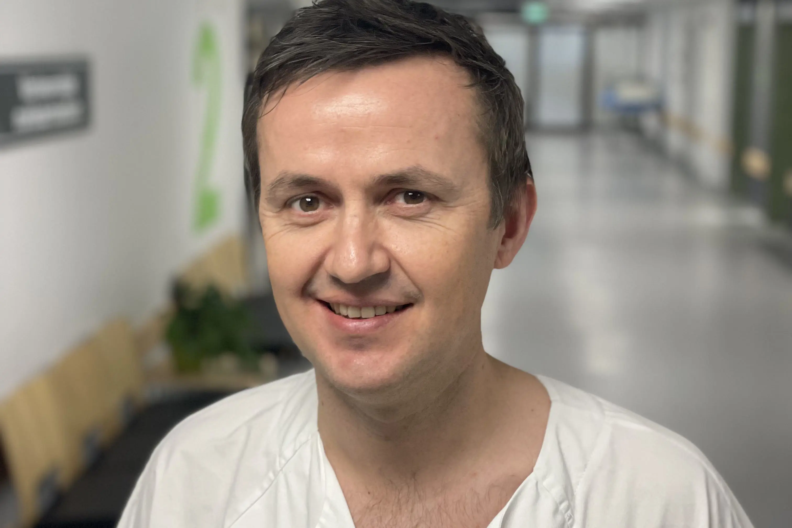 Overlege Audun Hasund kledd i hvit uniform utenfor gastrolaben ved sykehuset i Kristiansand. Foto.