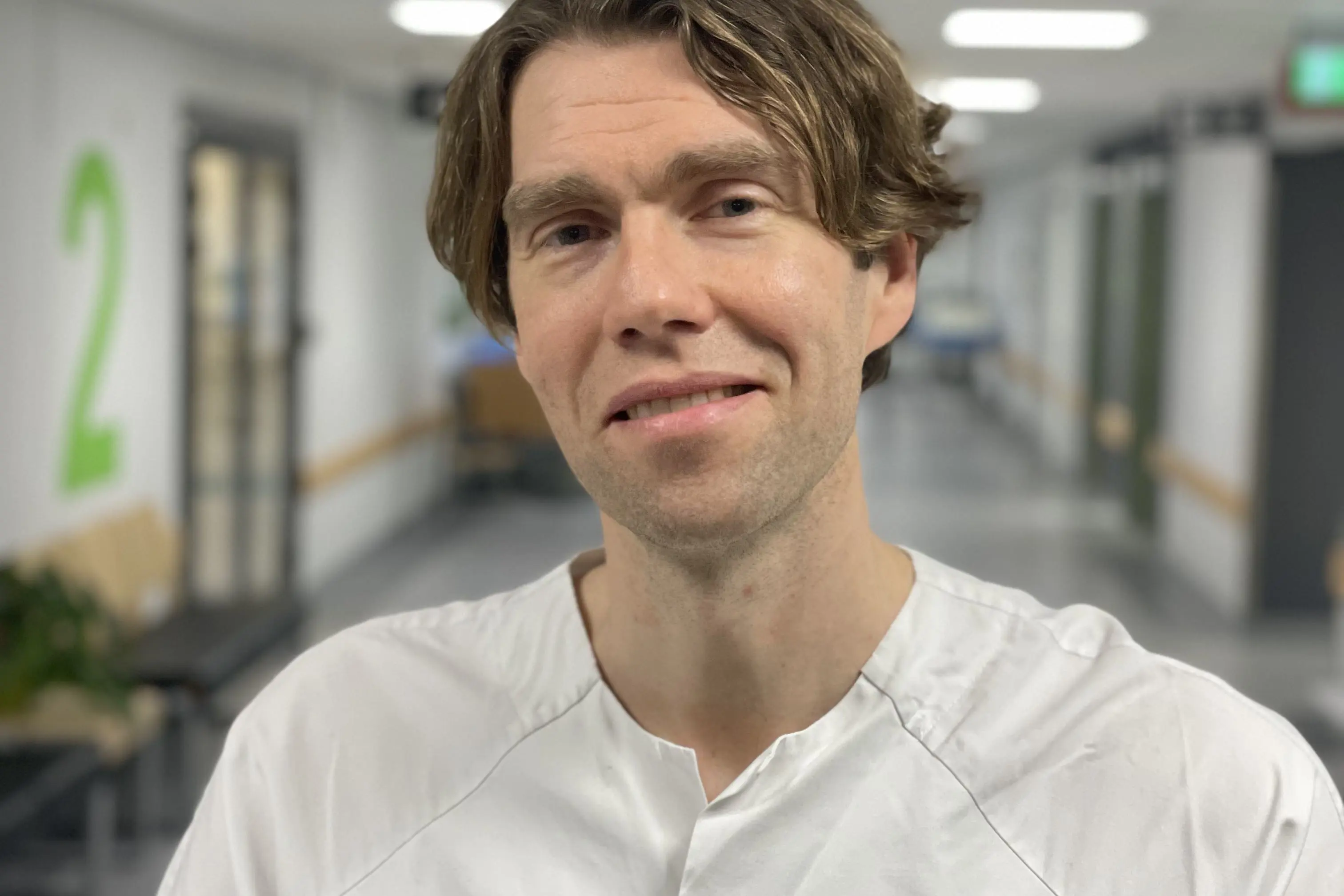 Overlege kledd i hvitt stående i sykehusets korridor. Foto.