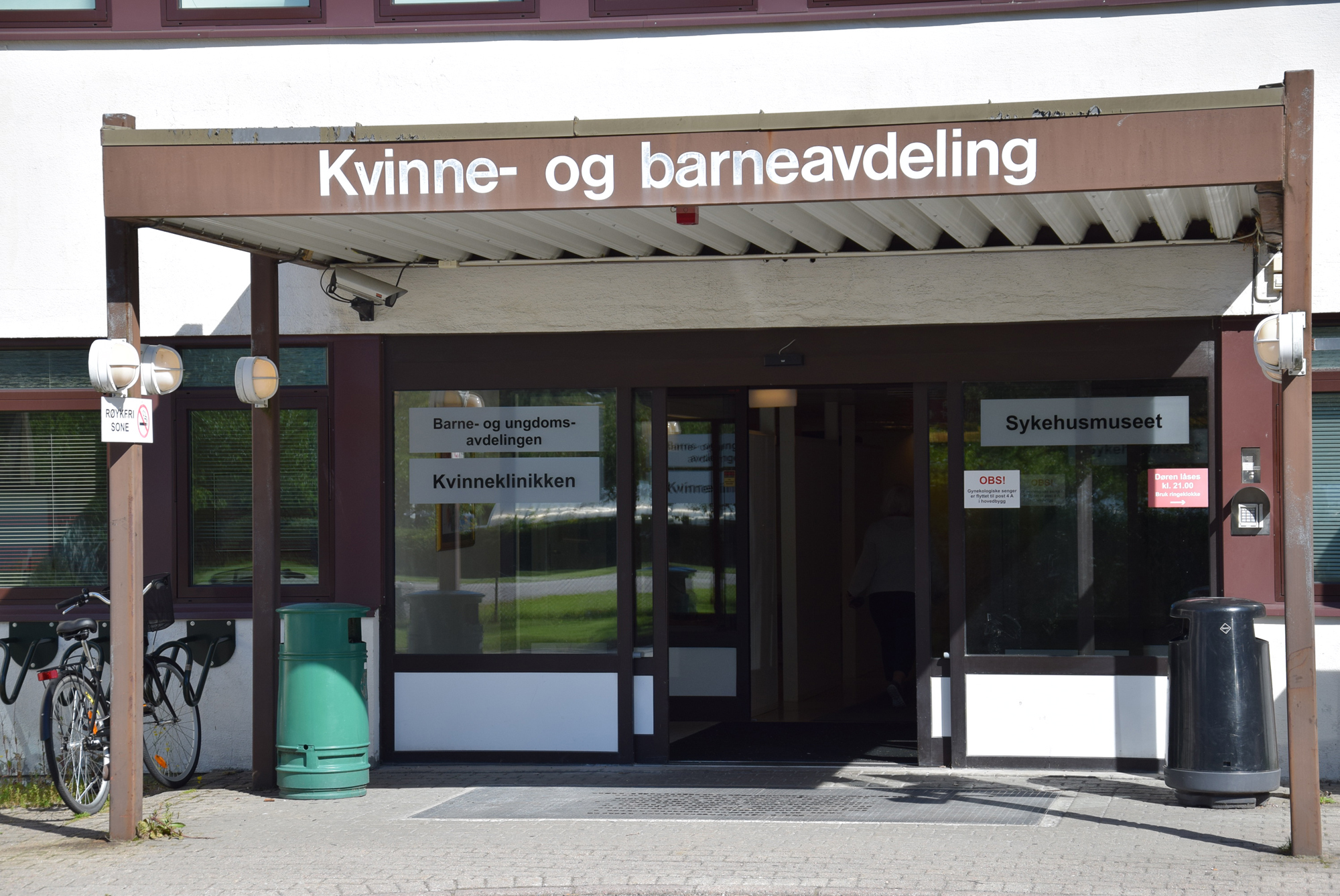 Skilt på murbygg med skriften Kvinne- og barneavdeling. Inngang under skilt. Foto.