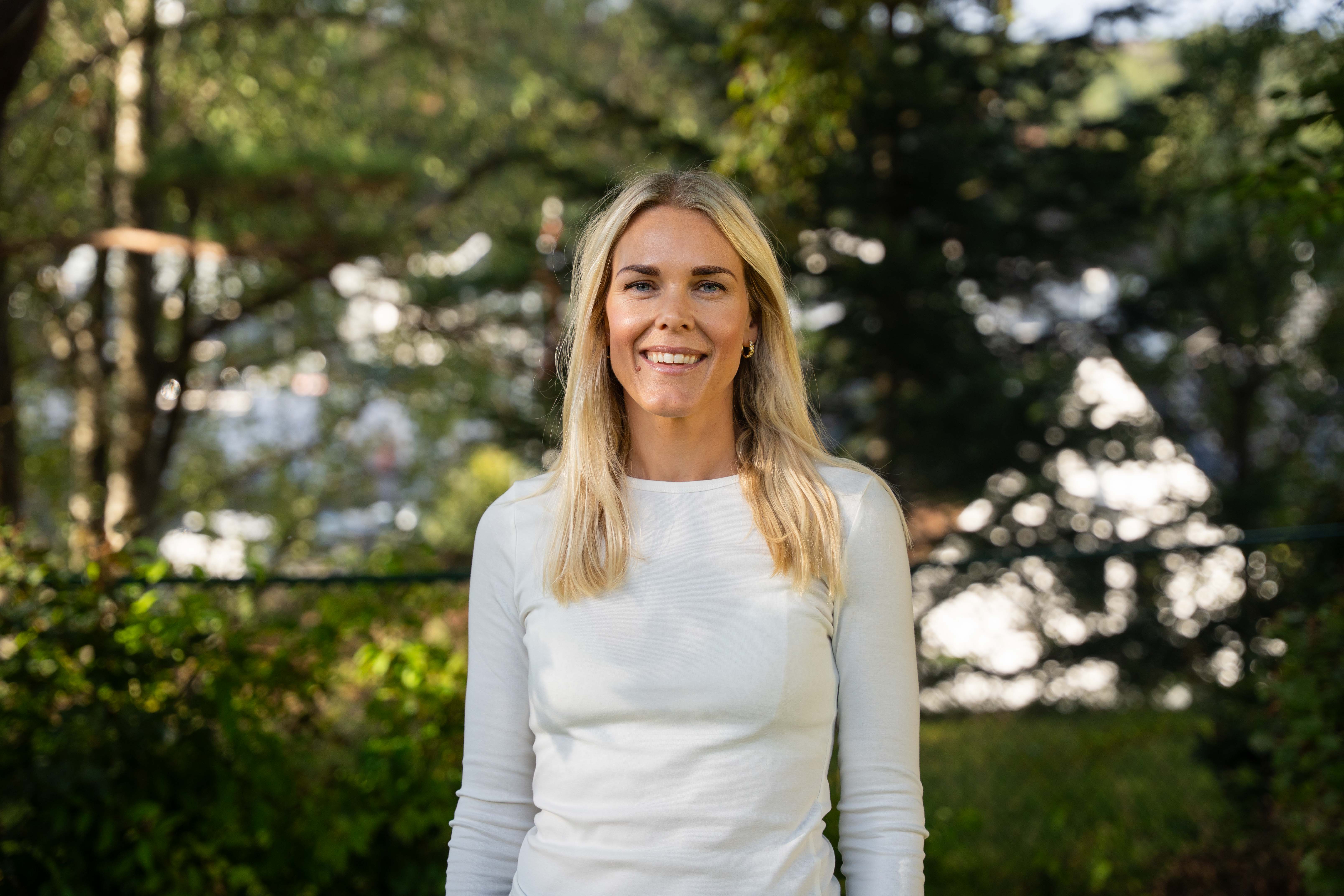 En kvinne som smiler foran trær