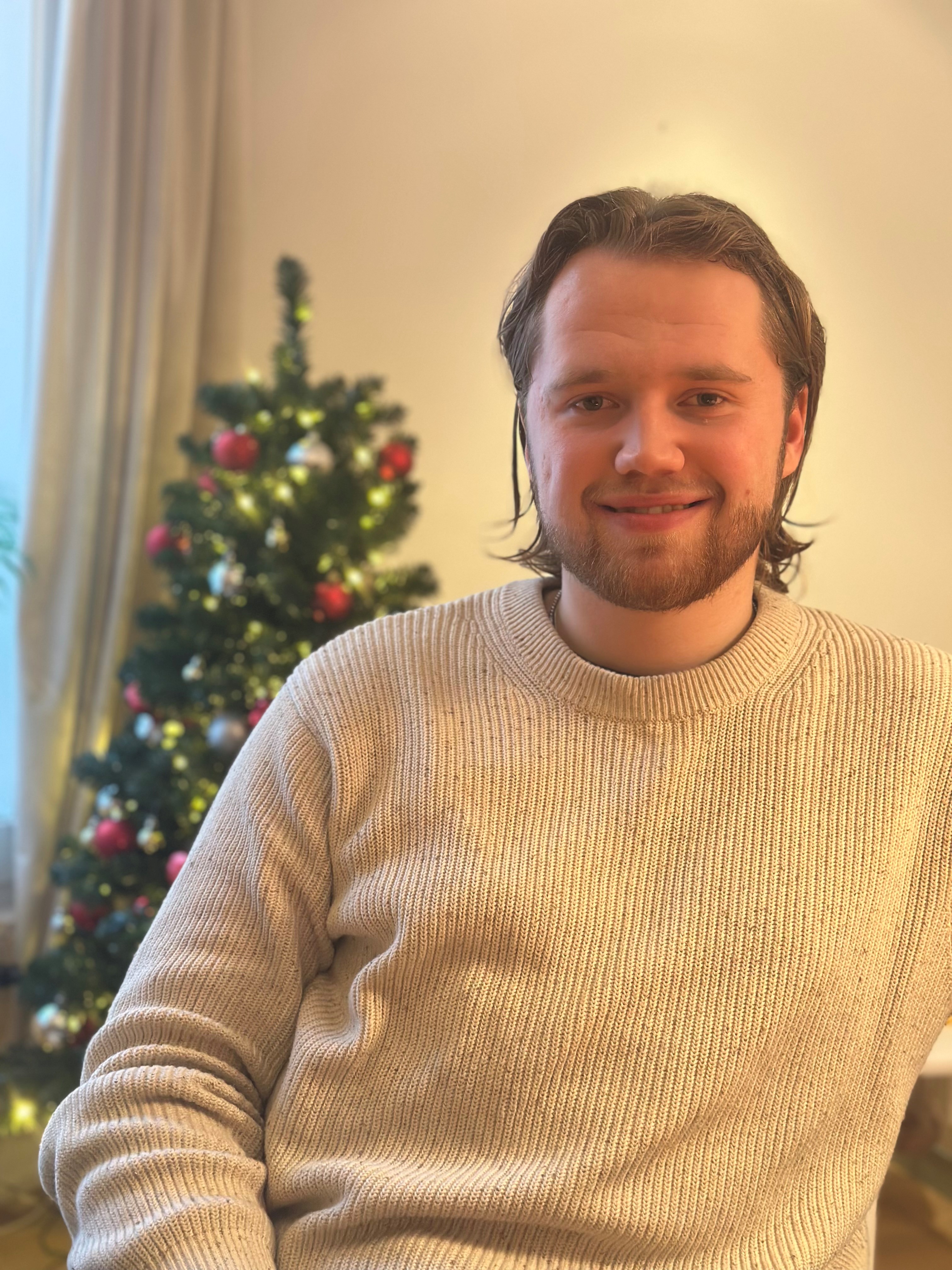 En mann som smiler foran et juletre